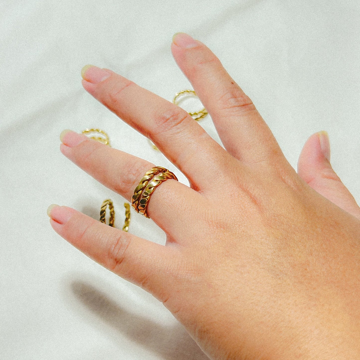 Hand wearing gold rings on a white background