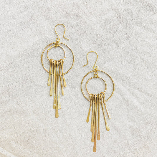 Gold hoop earrings with dangling elements on a light gray background
