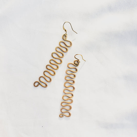 Gold wavy earrings on a light gray background